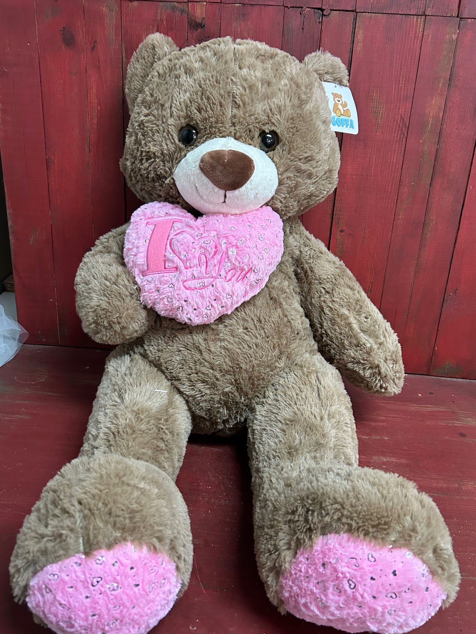 Large teddy bear holding a pink heart pillow