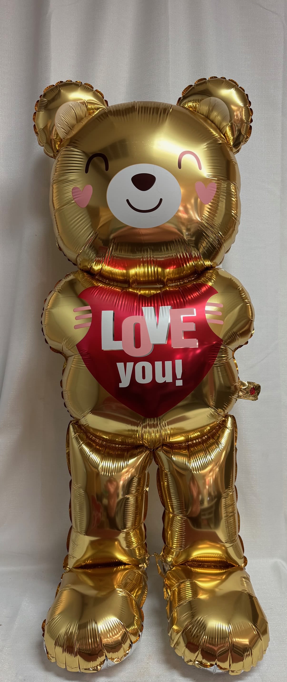 Gold teddy bear balloon holding a red heart that says "LOVE you!"