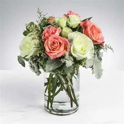 Pink and pale green roses arranged in a clear glass vase