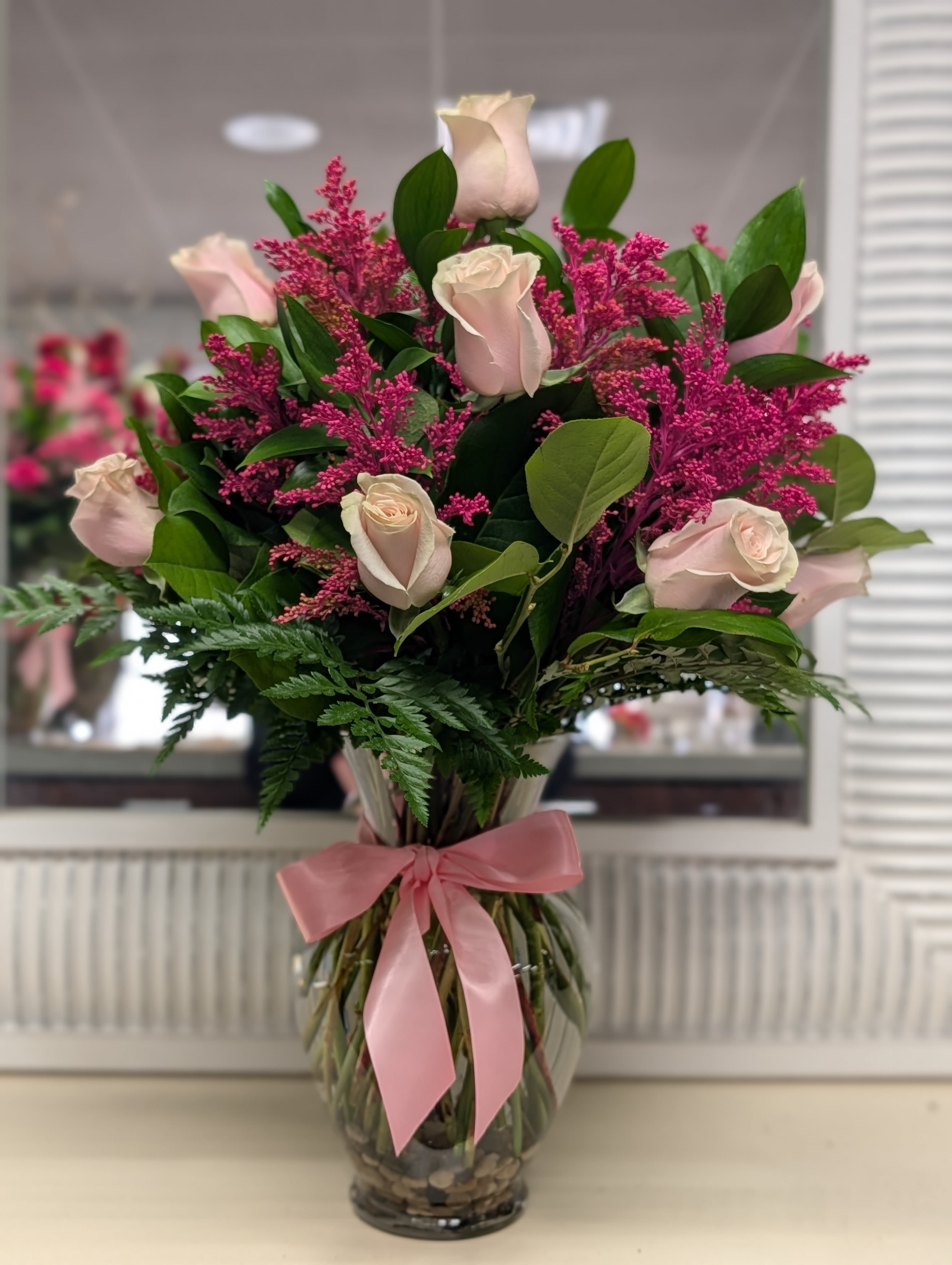 Pink roses and magenta filler in a glass vase with a pink ribbon