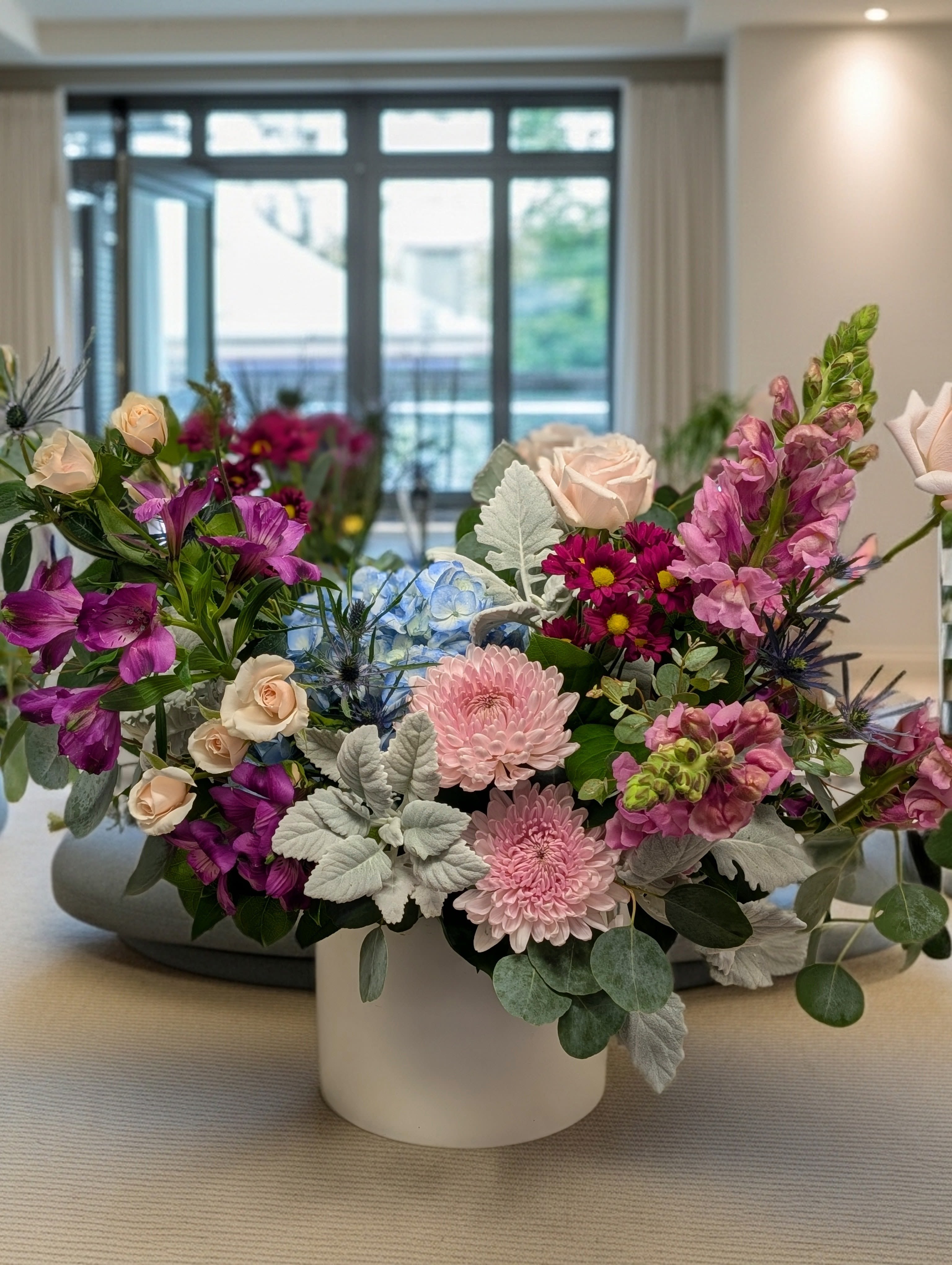 Mixed bouquet in a white vase with pink, purple, and blue flowers
