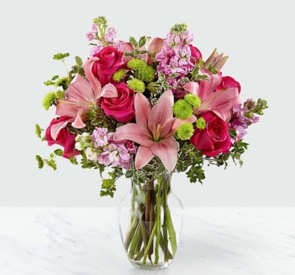 Pink roses and lilies arranged in a clear glass vase