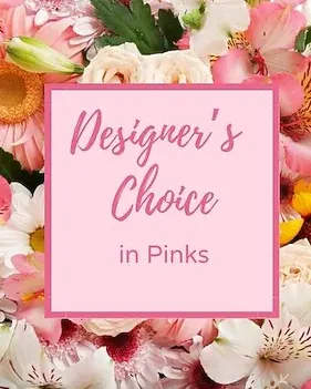 In PInks  - A joyful celebration of pinks and pastels-this flower arrangement puts a dense, layered mix of daisies, lilies, alstroemeria, and roses around a centered printed sign reading "Designer's Choice in Pinks." Perfect as a birthday bouquet, a thank-you gift, or a just-because surprise, the composition reads feminine and cheerful so the person you're thinking of will feel noticed and celebrated the moment they see it.  Soft pinks are the star, balanced with touches of white, sunny yellow, and warm orange for brightness and contrast. Large daisy-like blooms and pale lilies give air and texture while alstroemeria and roses add delicate detail; the arrangement is full and rounded with a lush, mixed-bouquet look that suits tabletop display or a focal gift. The included printed sign makes the sentiment clear and adds a festive, personalized touch.  Choose this piece when you want to send warmth and appreciation-ideal for friends, moms, coworkers, or anyone who loves pink florals. Standard care: keep in fresh water, trim stems every few days, and display away from direct heat to extend bloom life.
