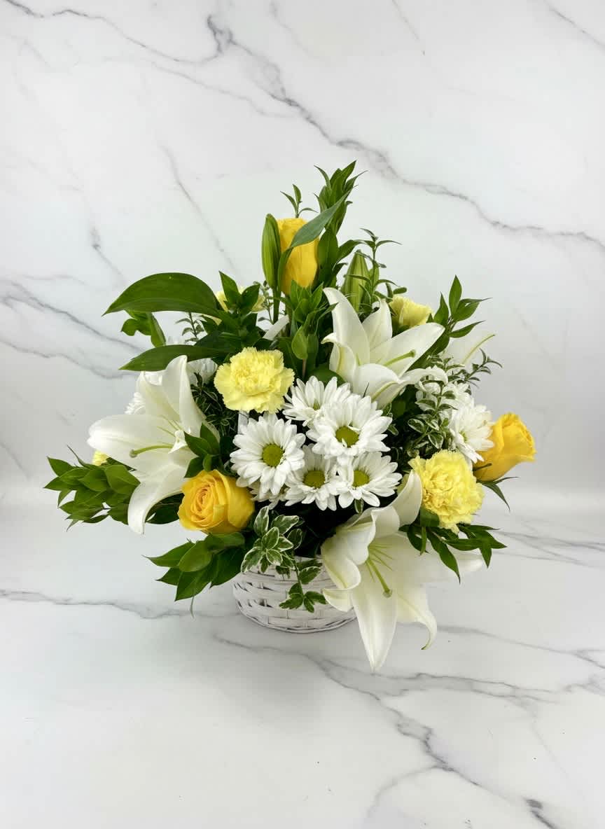 White lilies, yellow roses, and white daisies in a white basket