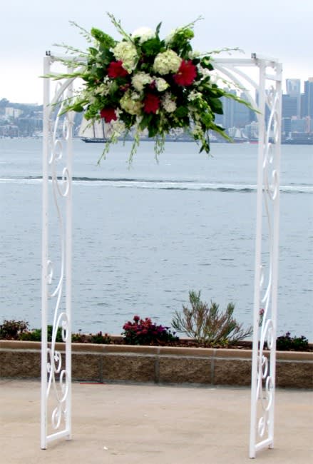 Floral arrangement on a white arch by the water