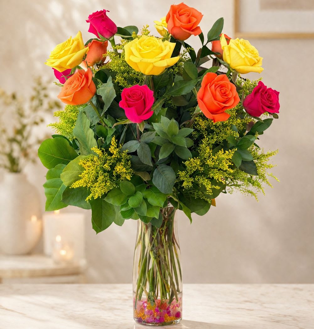The Sound of Joy - The Sound of Joy  Turn any occasion into a celebration with The Sound of Joy, a radiant bouquet bursting with vibrant color and happiness. Featuring premium long-stem Ecuadorian roses in brilliant shades of hot pink, yellow, and orange, this joyful arrangement is accented with golden Solidago and fresh garden greens for added texture and charm.  A cheerful alternative to the traditional red rose bouquet, The Sound of Joy is the perfect gift for birthdays, congratulations, anniversaries, thank-you gifts, grand openings, or simply to brighten someone's day. Handcrafted by our designers and presented in a clear glass vase, this stunning arrangement is guaranteed to make a lasting impression.  Standard size measures approximately 18" (W) x 26" (H). Deluxe and Premium versions feature additional long-stem roses arranged in larger glass vases for an even more spectacular display.  Available Sizes:  • Standard – One Dozen (12) Long Stem Hot Pink, Yellow &amp; Orange Roses, Solidago &amp; Fresh Garden Greens Glass Vase  • Deluxe – Two Dozen (24) Long Stem Hot Pink, Yellow &amp; Orange Roses, Solidago &amp; Fresh Garden Greens Glass Vase  • Premium – Three Dozen (36) Long Stem Hot Pink, Yellow &amp; Orange Roses, Solidago &amp; Fresh Garden Greens Large Glass Vase  Bold, colorful, and overflowing with happiness, The Sound of Joy is a vibrant expression of celebration, gratitude, and unforgettable moments.