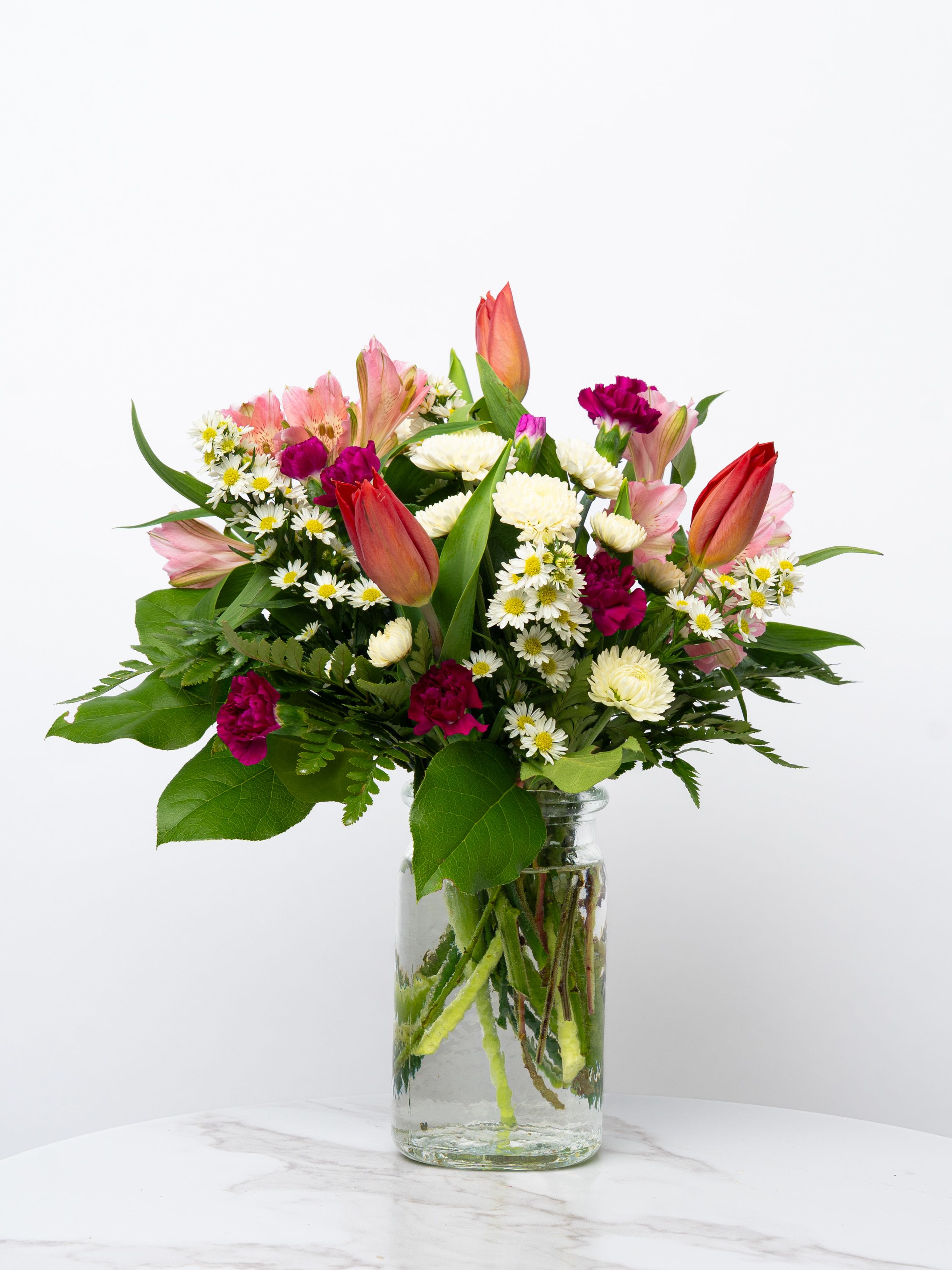 Mixed bouquet of pink and white flowers in a clear glass vase