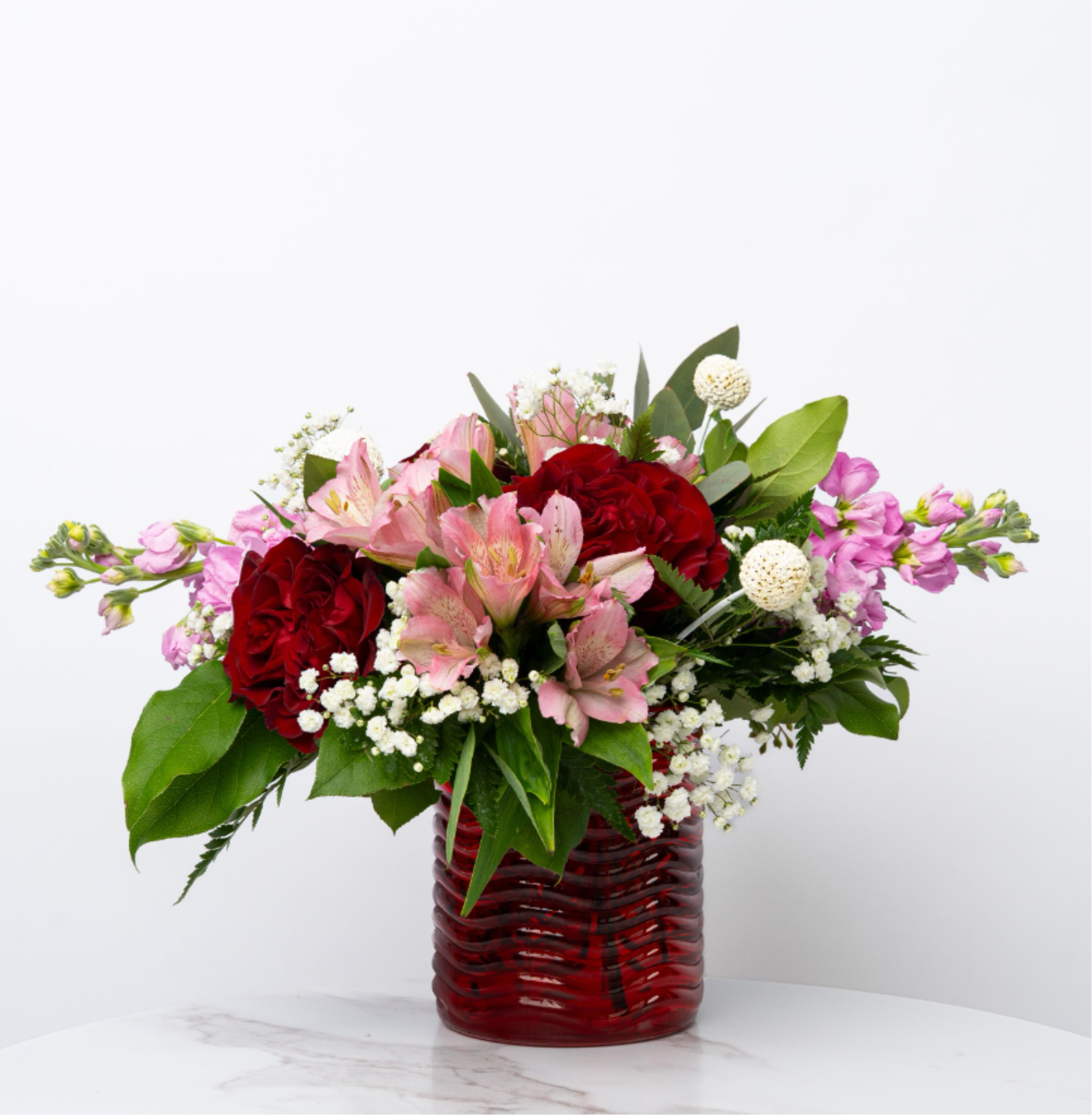 Our Valentine's Day Collection: The Emma - Looking for a charming, thoughtful gesture this Valentine’s Day? The Emma pairs a delicate mix of florals and roses with a striking red glass cylinder, capturing the wit, grace, and playful spirit of Jane Austen’s beloved heroine. A best-seller for its perfect size and effortless elegance, this arrangement blends classic romance with a touch of whimsy, making every bouquet feel like a personal love letter in bloom.  At Schultz Floral, we believe in two things: high quality blooms and real photography of our products. Each arrangement is one of a kind and styled just for your order in our Valparaiso Shop, so your final arrangement may not look exactly as pictured due to daily availability. 