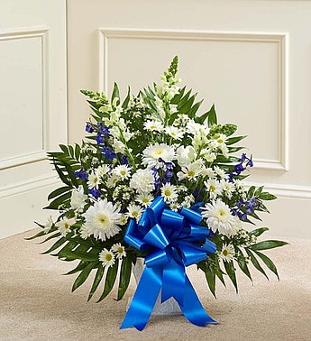 White daisy arrangement with blue ribbon in a container