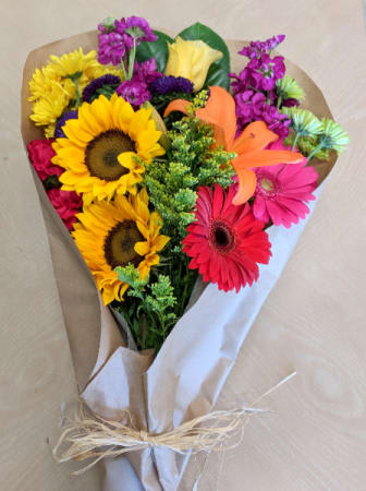 Bouquet of sunflowers, gerbera daisies, and mixed blooms wrapped in paper