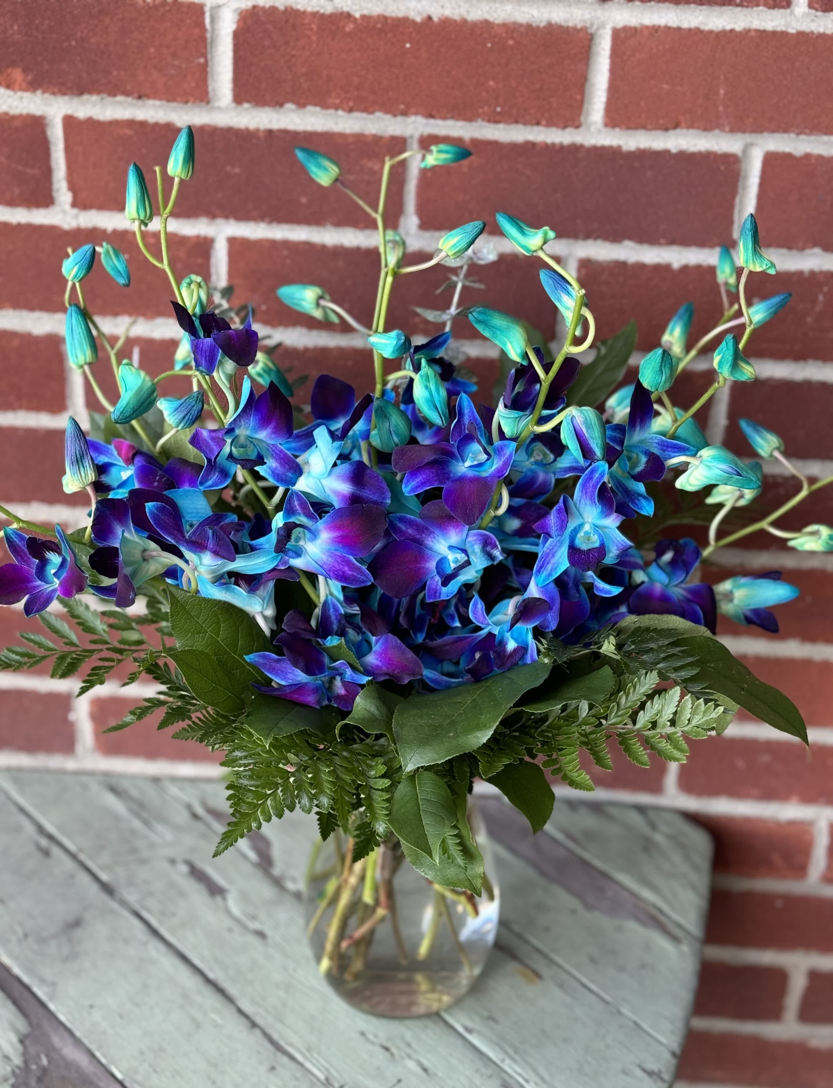 Blue and purple orchid bouquet in a clear glass vase