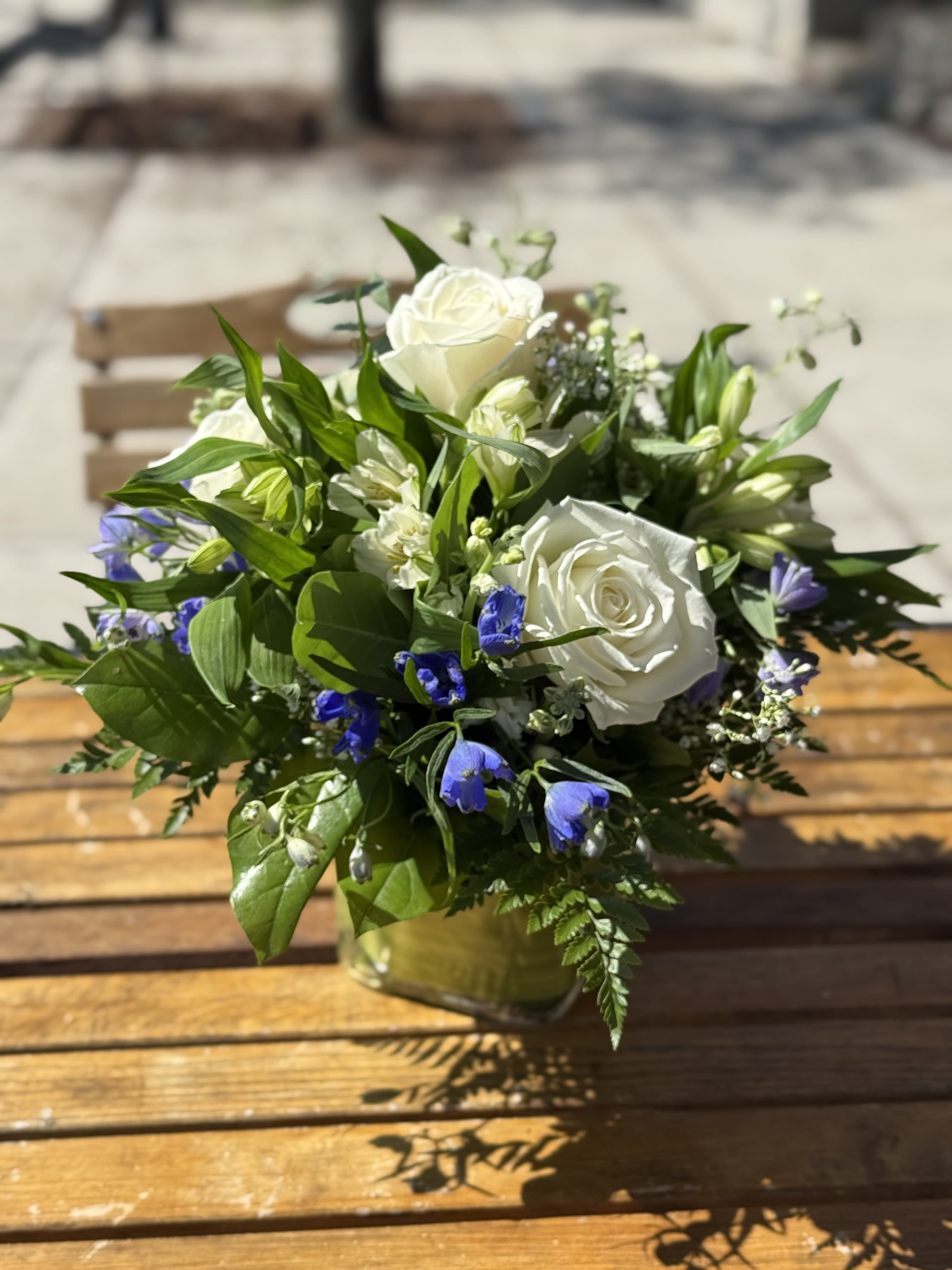 White roses and blue flowers arranged in a glass vase