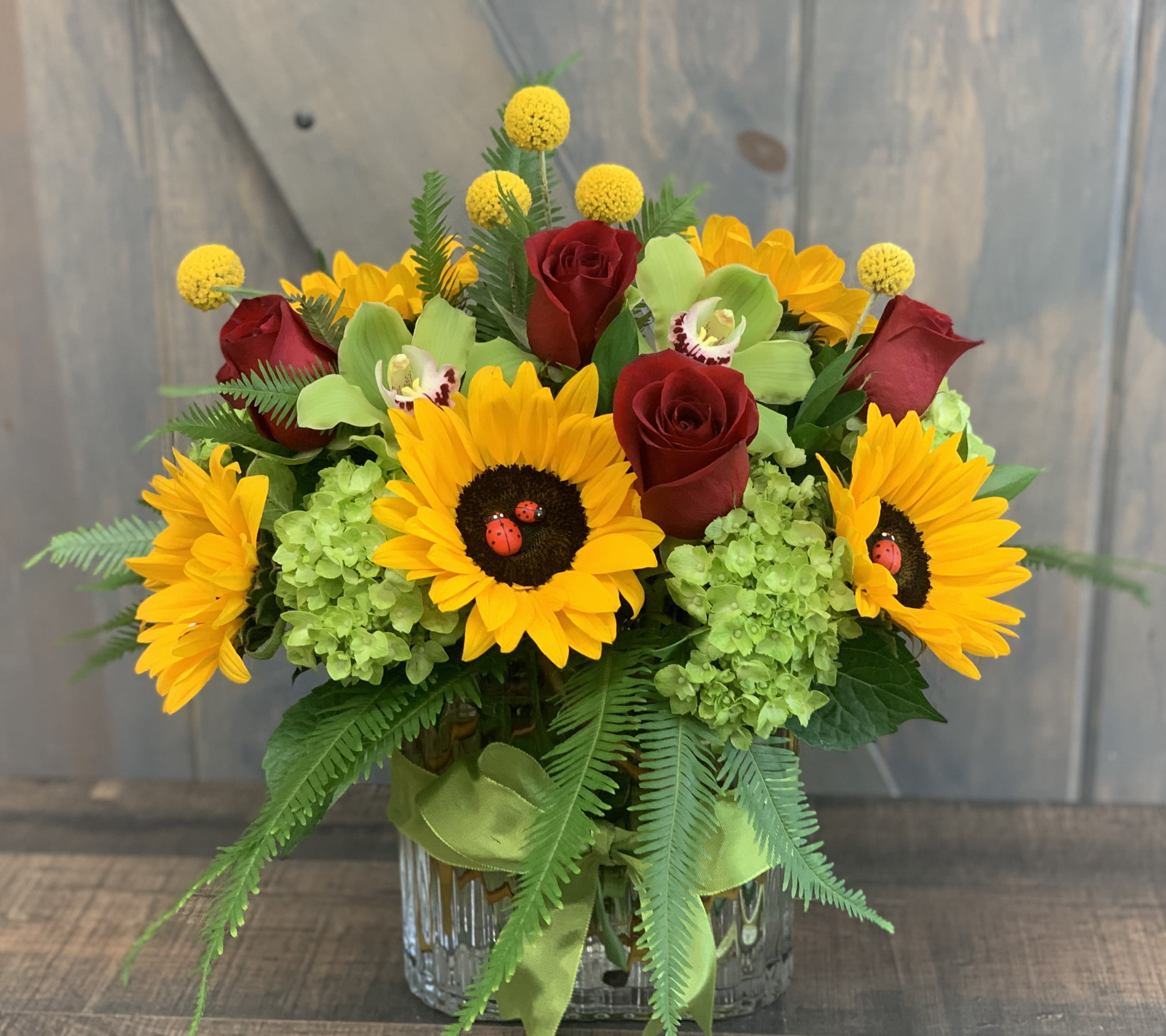 Bouquet of sunflowers and red roses in a glass vase