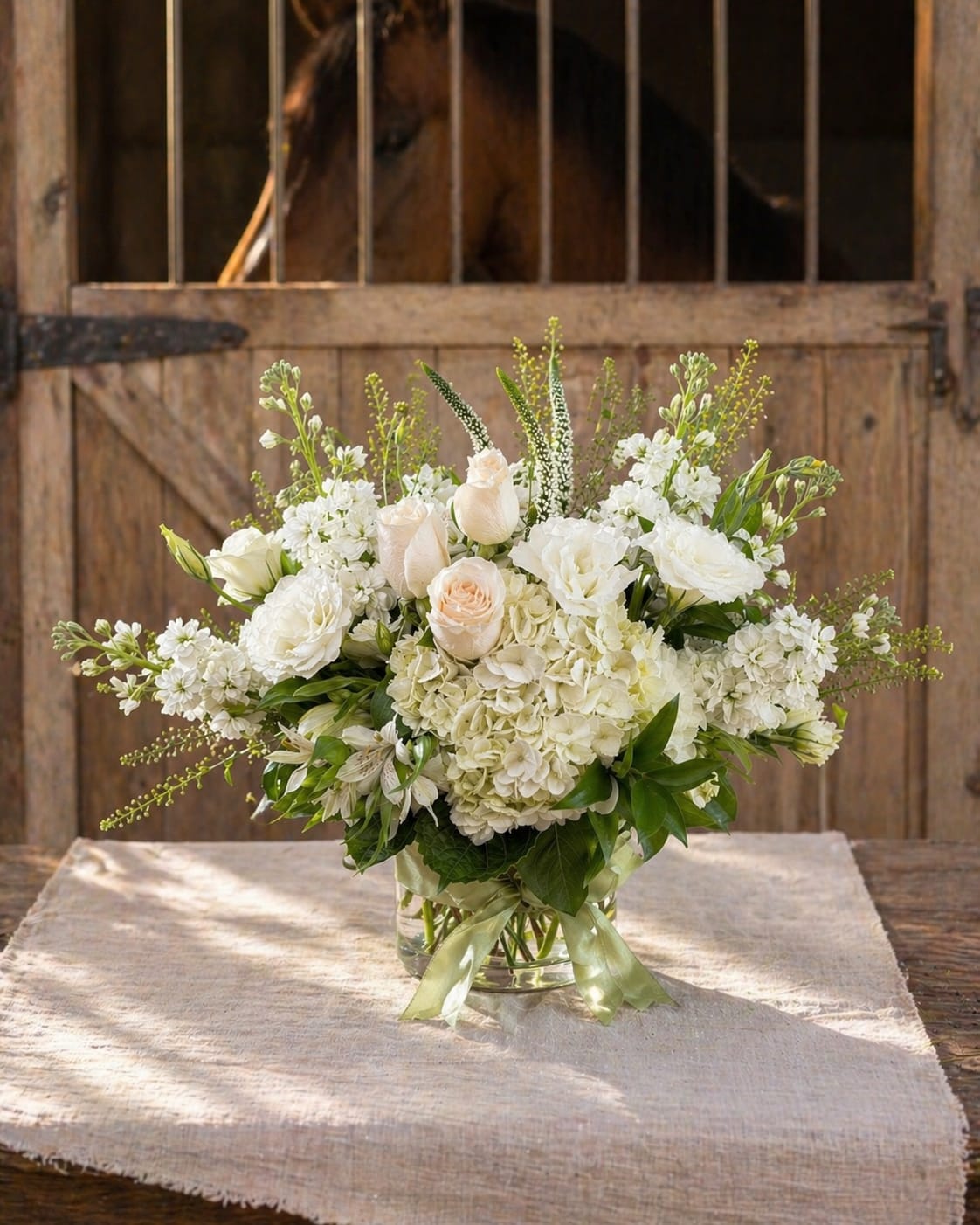 Palos Verdes Bridle - Palos Verdes Bridle Inspired by the quiet elegance of the Palos Verdes bridle trails, this refined arrangement blends soft whites and fresh garden textures for a timeless Mother’s Day statement. Designed in a clear glass cylinder vase, it features white hydrangea, roses, lisianthus, stock, alstroemeria, veronica, and lepidium—creating a graceful balance of lush blooms and airy movement. Romantic, organic, and effortlessly sophisticated, this arrangement brings the charm of coastal equestrian beauty indoors.