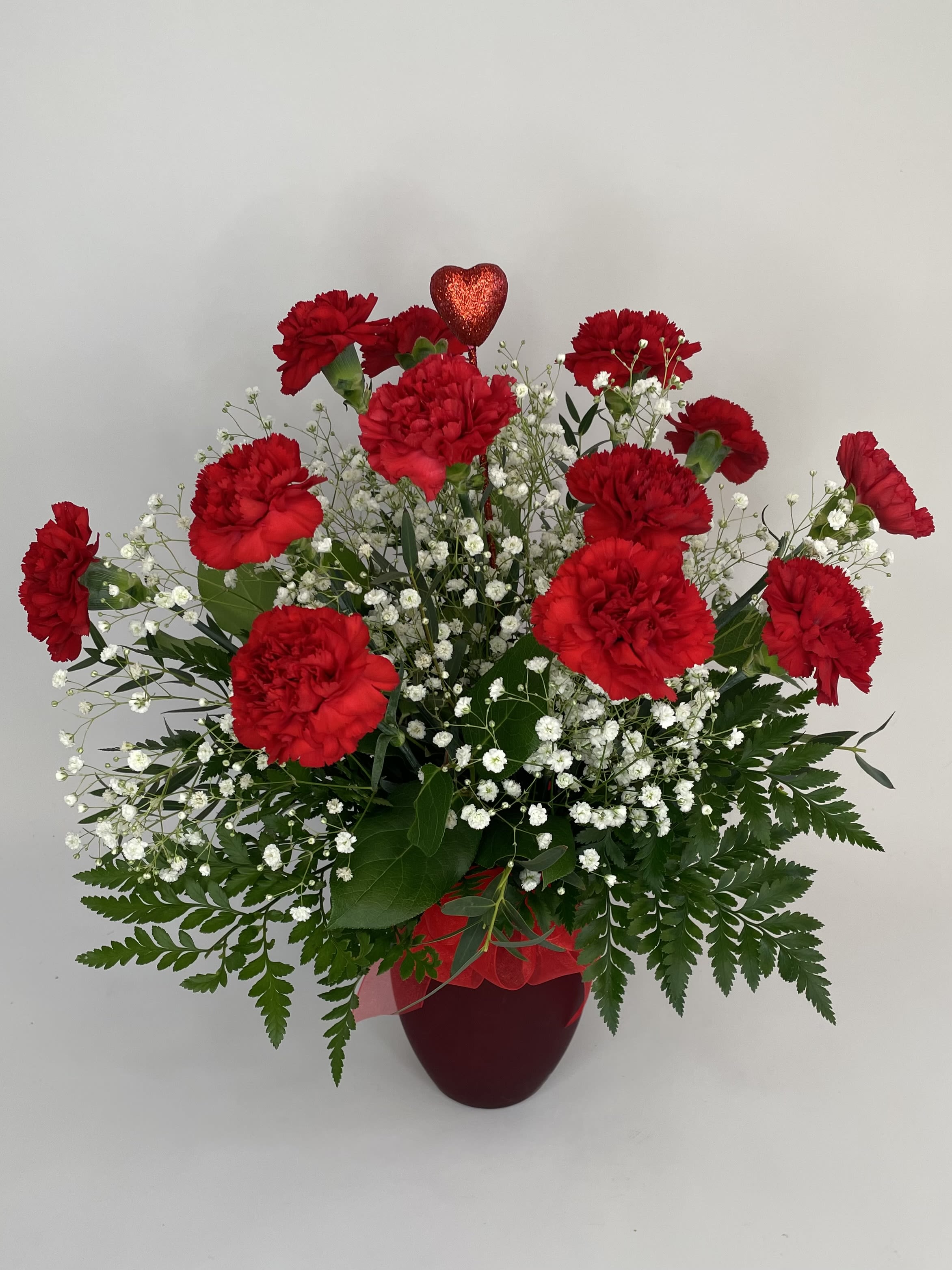 Charming Carnations - A dozen charming carnations arranged in a ruby red vase to showcase their beauty. Glitter heart included!