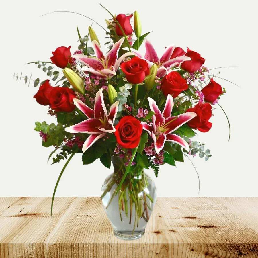 Red roses and pink lilies in a clear glass vase