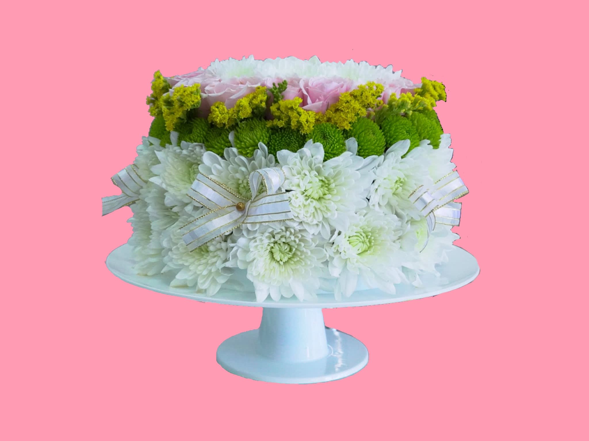 White and green floral arrangement on a pedestal stand with ribbon bows