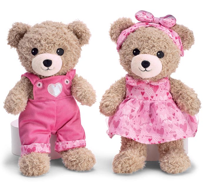 Two teddy bears in pink outfits, one in overalls and one in a dress