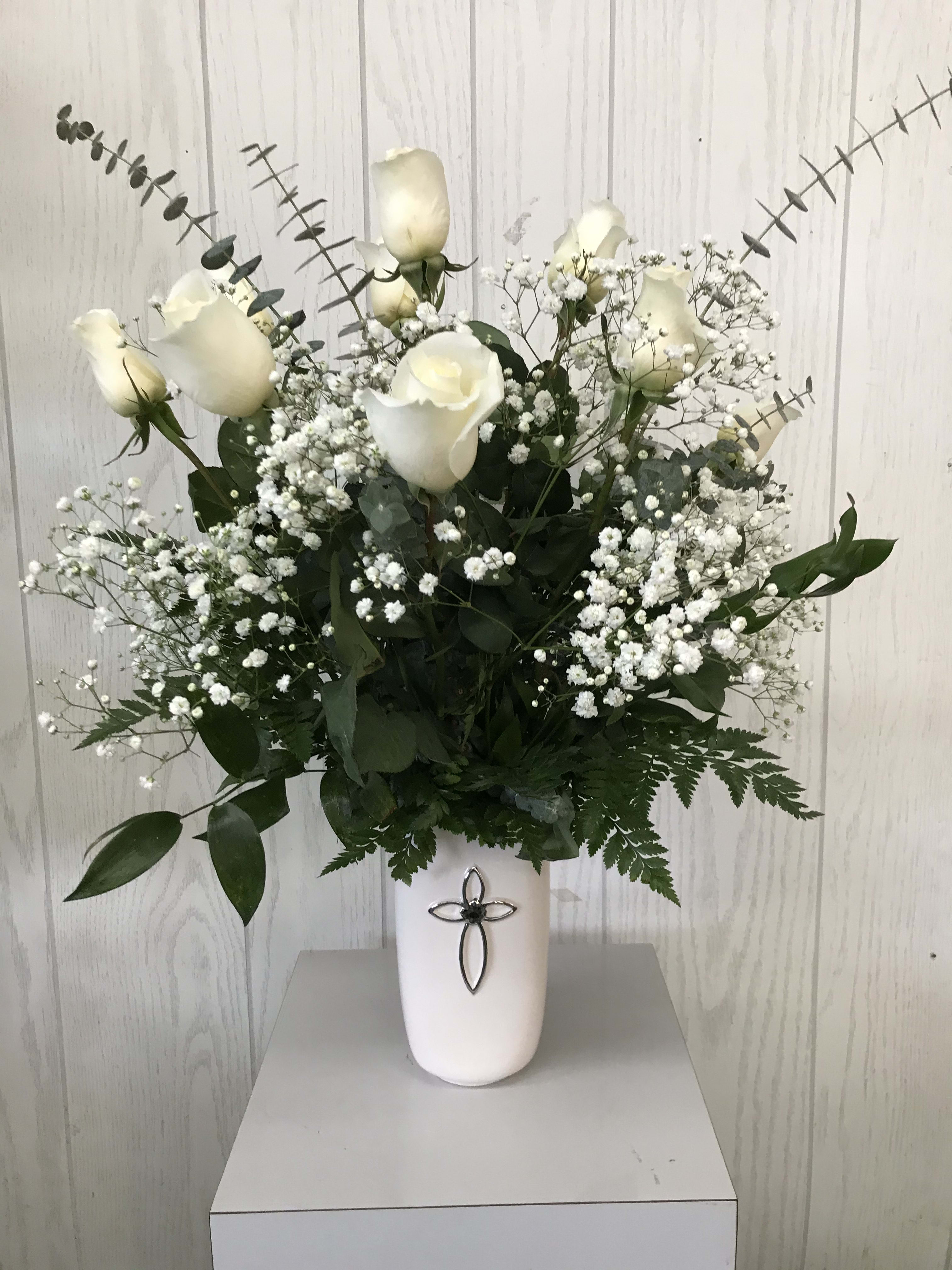 White roses and baby's breath arranged in a white vase.