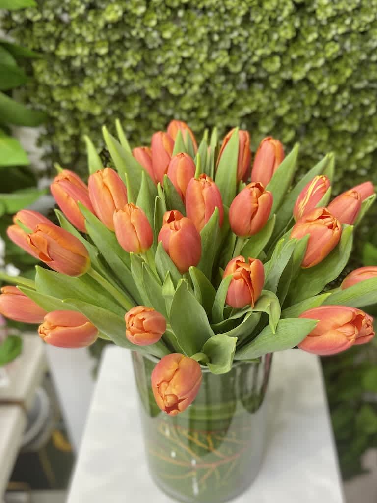 Bouquet of orange tulips arranged in a clear glass cylinder vase