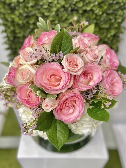 Round arrangement of pink roses with white blooms in a clear glass vase