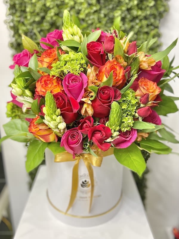 Bright pink and orange mixed bouquet in a white hatbox with gold ribbon
