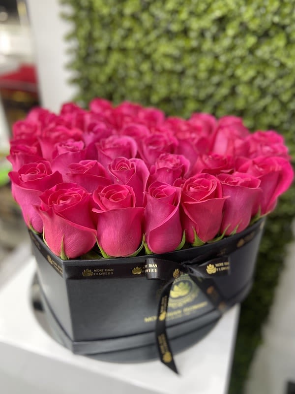Heart-shaped black box filled with tightly packed hot pink roses