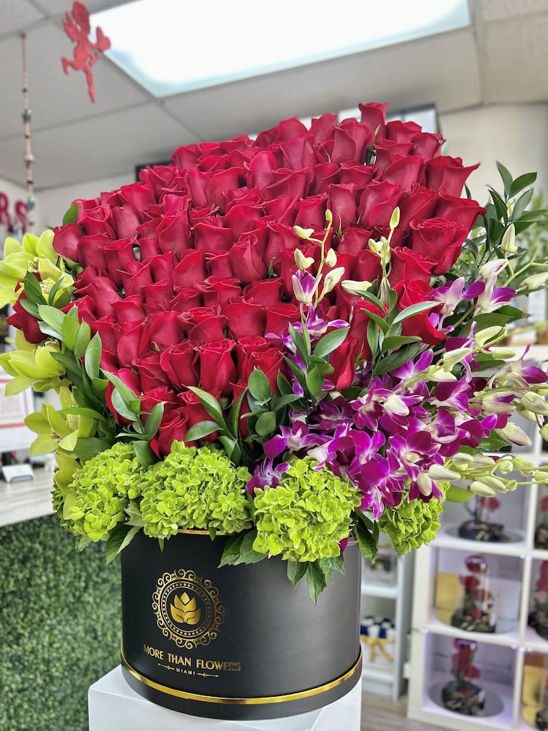Large hatbox arrangement of red roses with green hydrangeas and purple orchids in a black round box