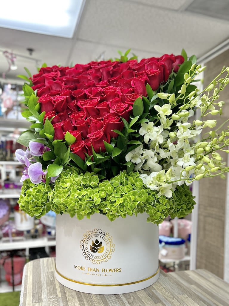 Tall hatbox arrangement of red roses, green hydrangeas, and white and purple orchids in a white box
