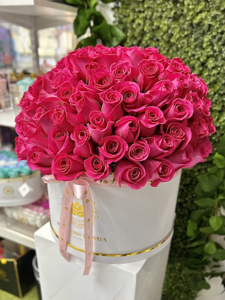 Large arrangement of hot pink roses in a white hat box with a pink ribbon
