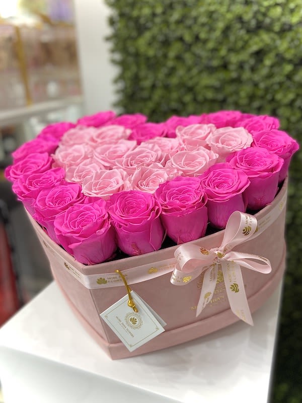 Heart-shaped box of bright and light pink roses with ribbon and tag