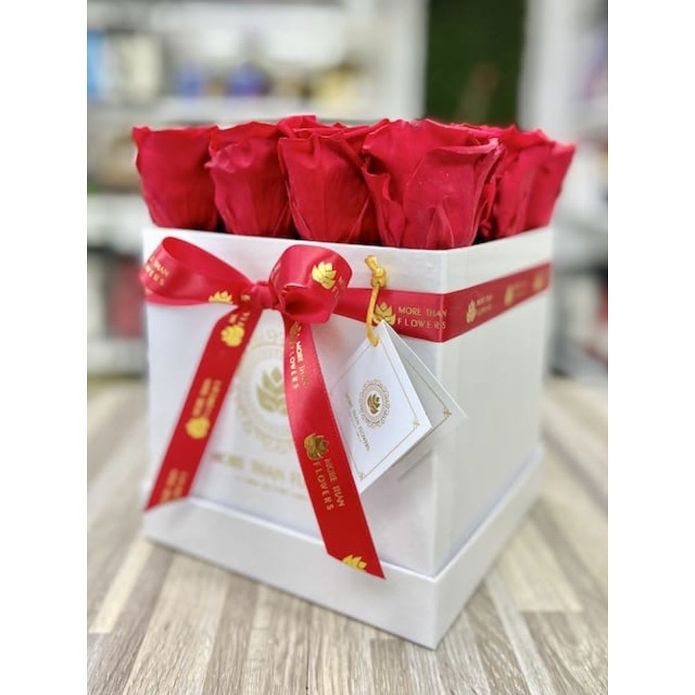 Box arrangement of red roses in a white square gift box with red ribbon and tag
