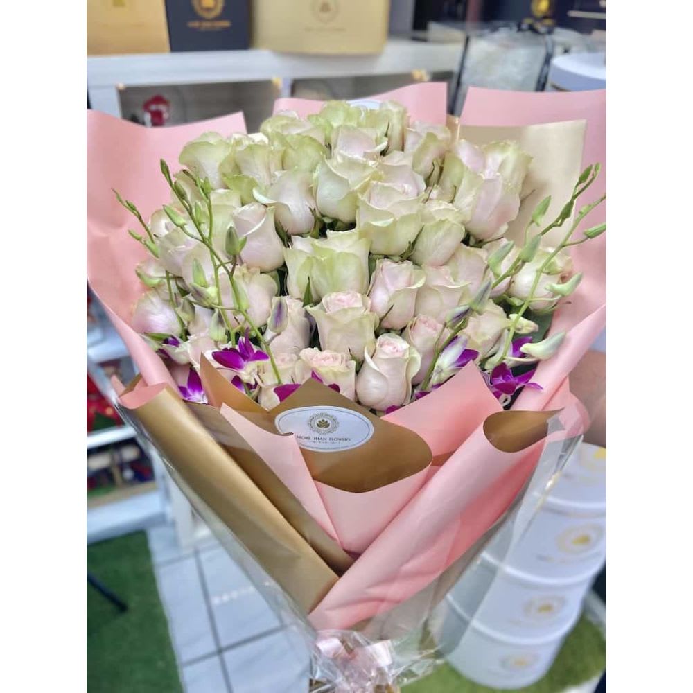 Large bouquet of pale pink roses with purple orchids wrapped in pink and gold paper