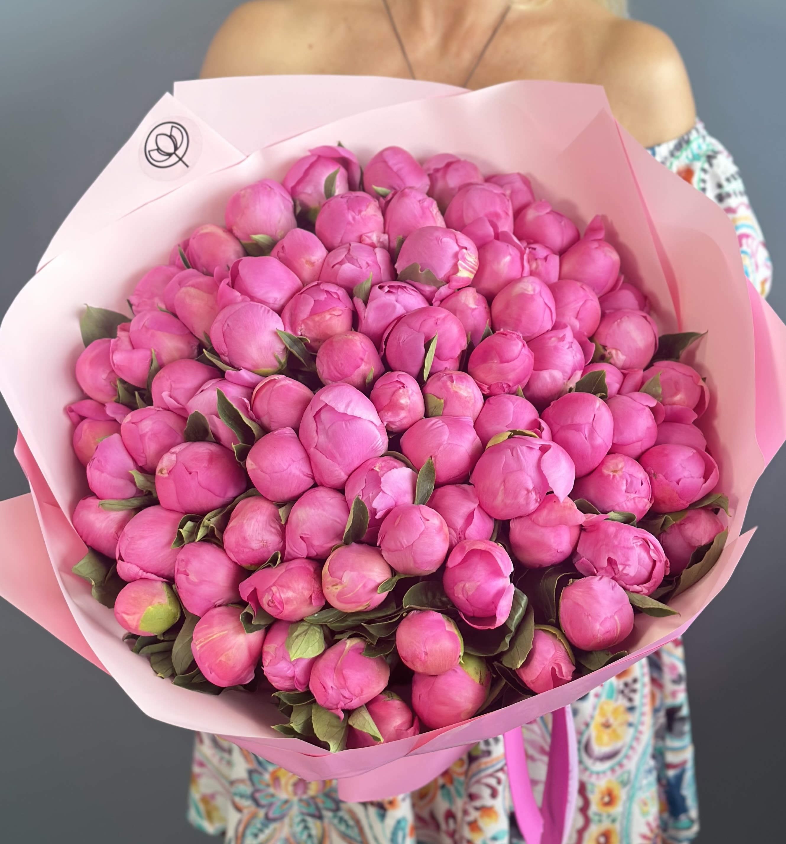 Large bouquet of bright pink peony buds wrapped in pale pink paper