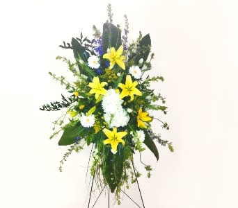 Standing spray of yellow lilies, white daisies, and white mums on a metal easel