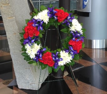 Patriotic standing wreath with red, white, and purple flowers on a metal easel