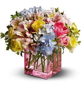 Mixed bouquet of roses, alstroemeria, and hydrangeas in a pink glass vase