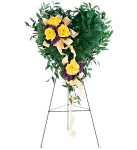 Heart-shaped leafy standing arrangement with yellow roses and ribbon on a metal easel