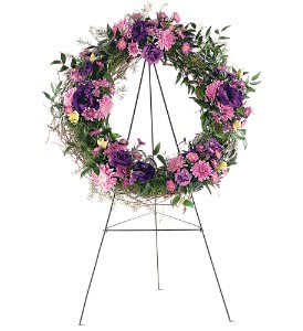 Standing wreath of purple and pink flowers on a black metal easel