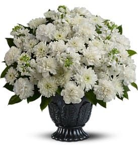 Large all-white carnation and chrysanthemum arrangement in a dark pedestal urn