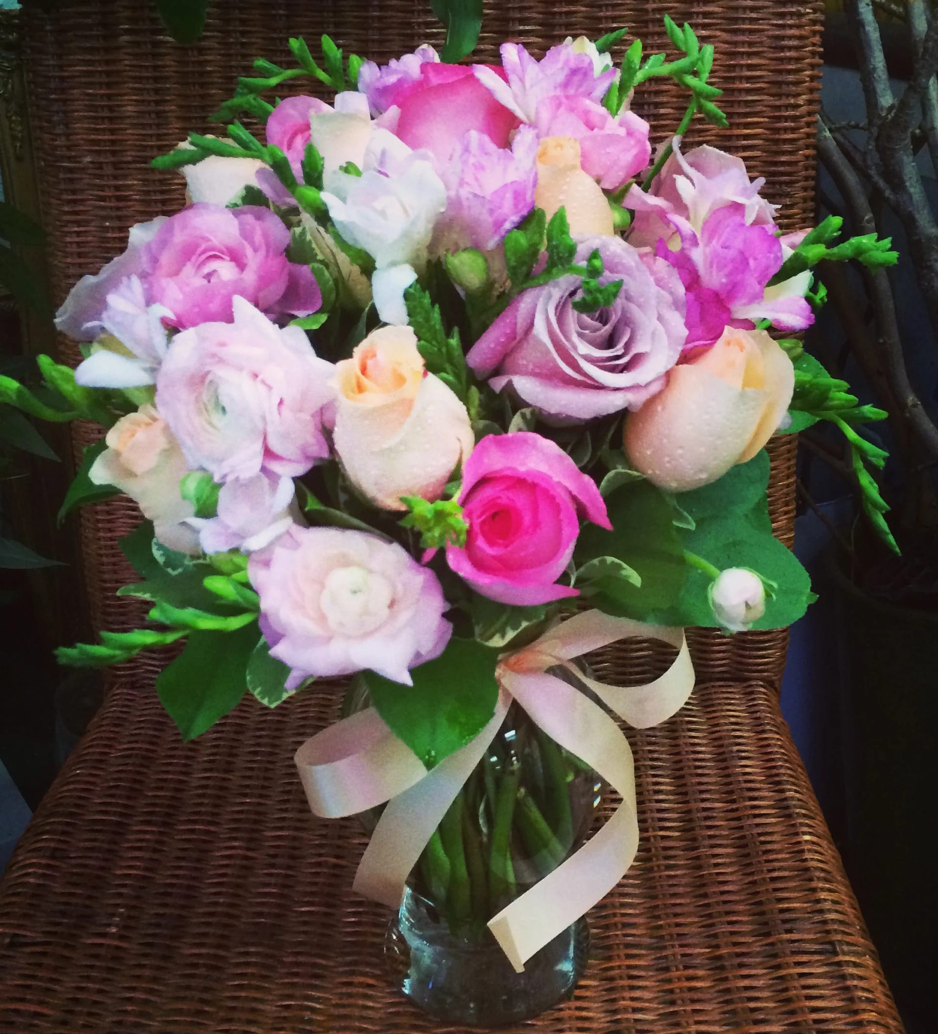 Pink and lavender bouquet in a glass vase with a ribbon