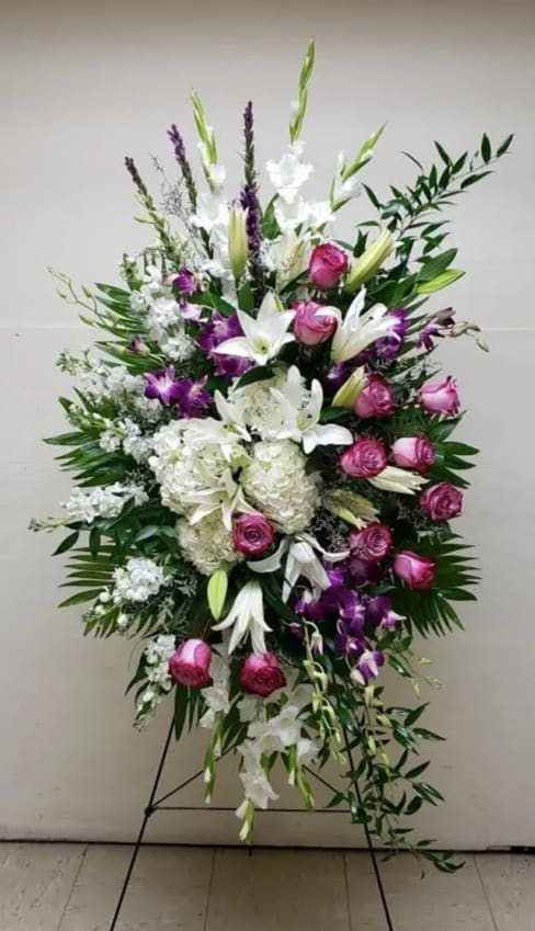 Tall standing floral spray with white lilies, pink roses, and purple orchids