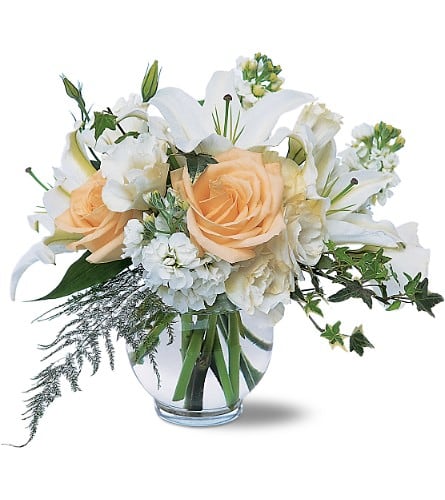 Peach roses and white lilies in a clear glass vase
