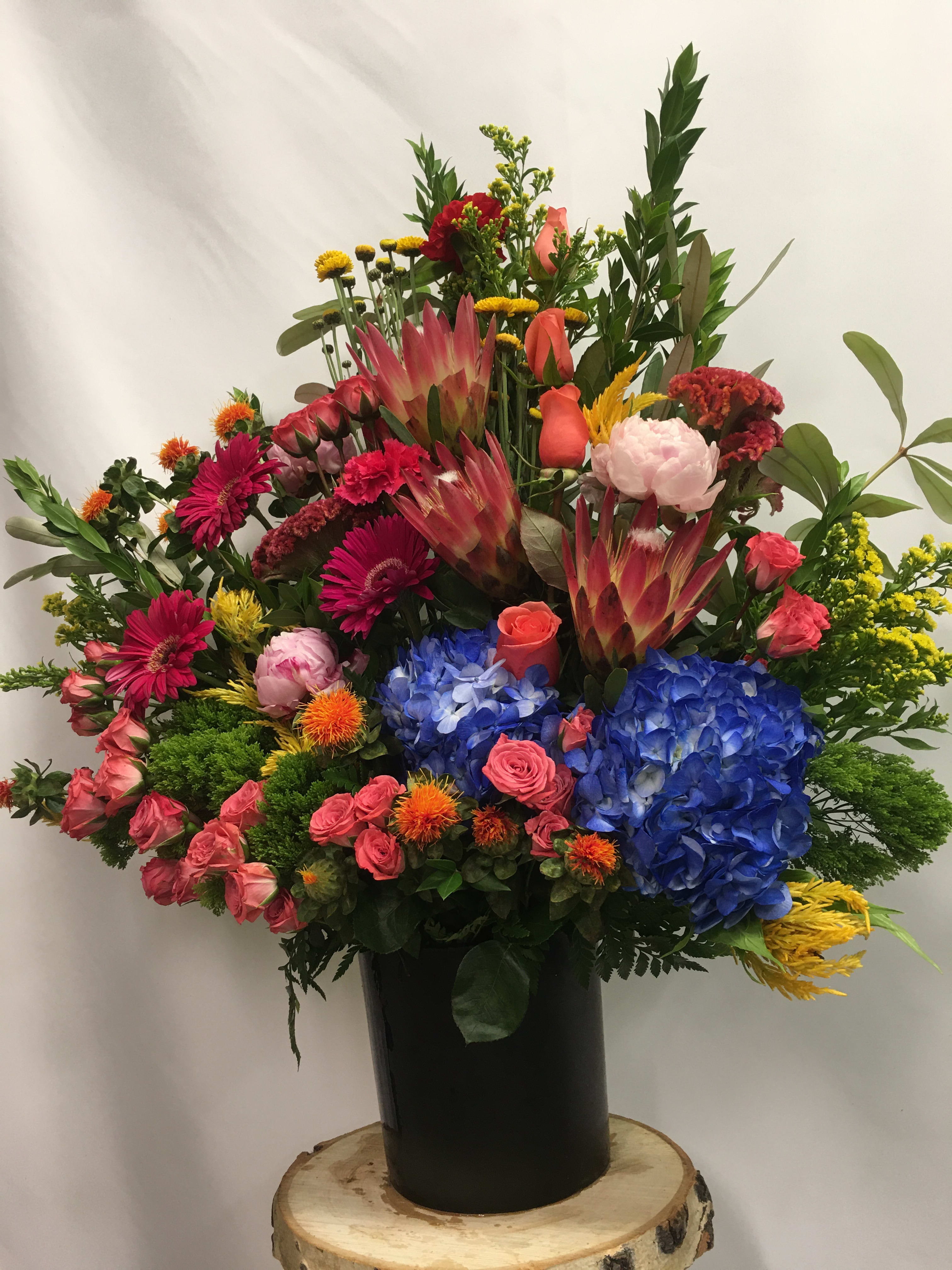 Large mixed bouquet in a black vase with blue hydrangeas and pink roses