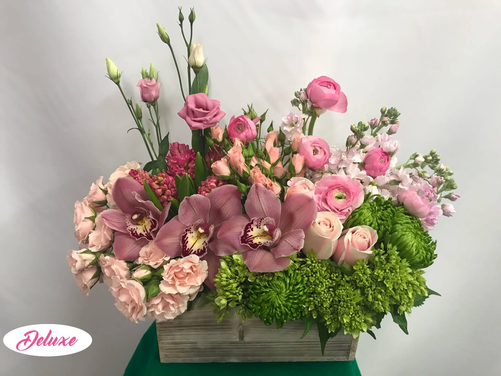 Pink and green mixed flower arrangement in a wooden box