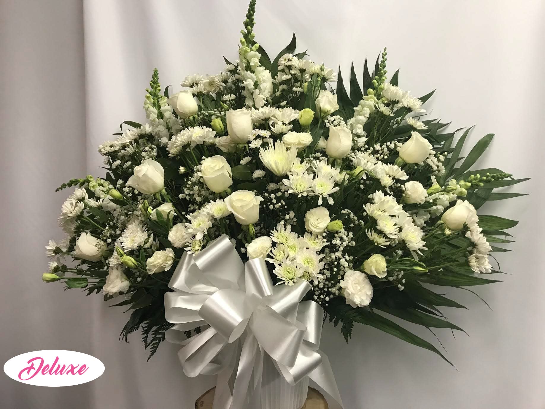 White floral spray with roses and daisies, finished with a silver bow