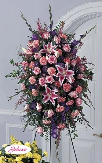 Tall standing floral spray with pink roses and lilies in pink, purple, and white.