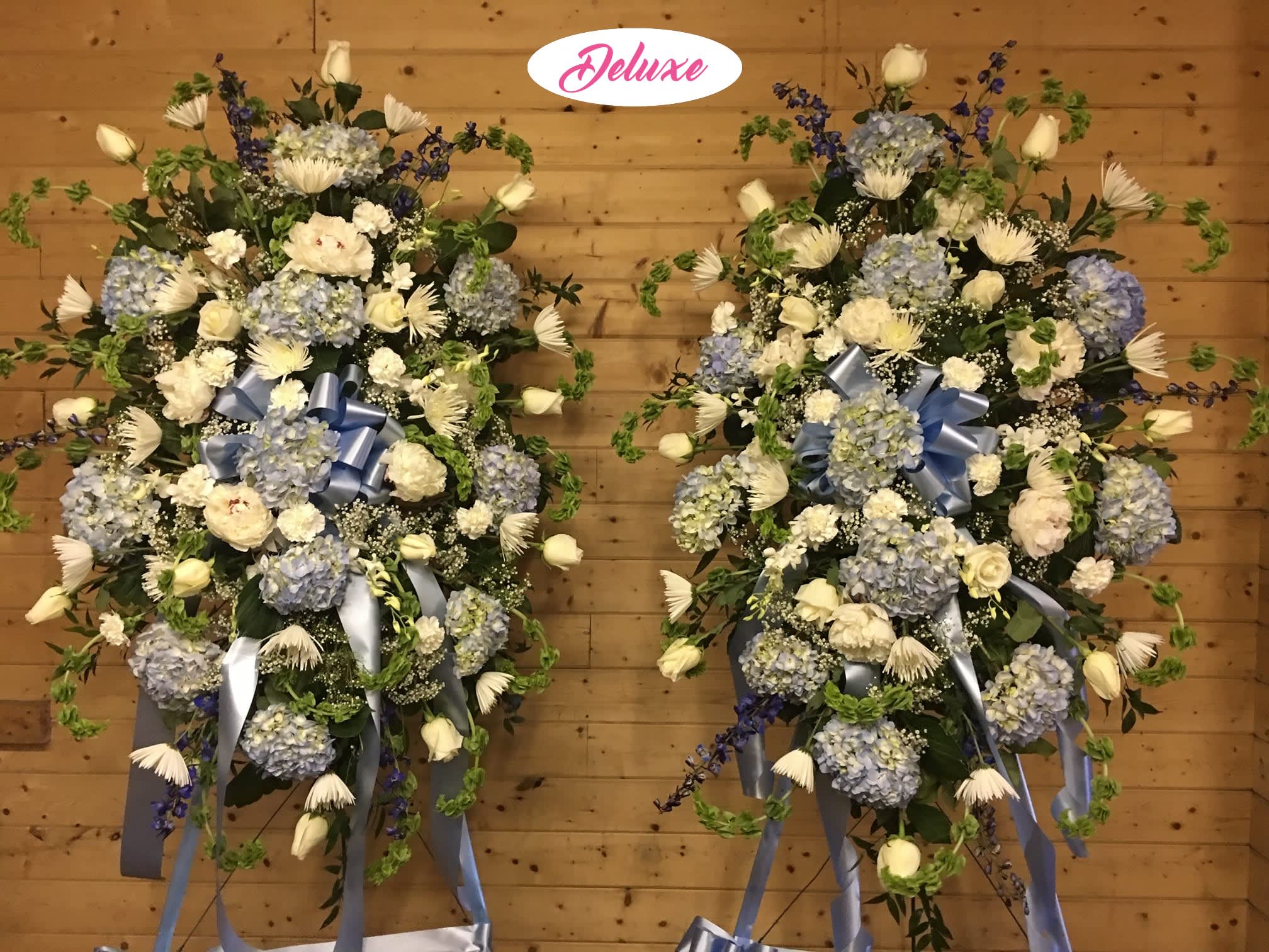Two large blue and white floral standing sprays with ribbon bows