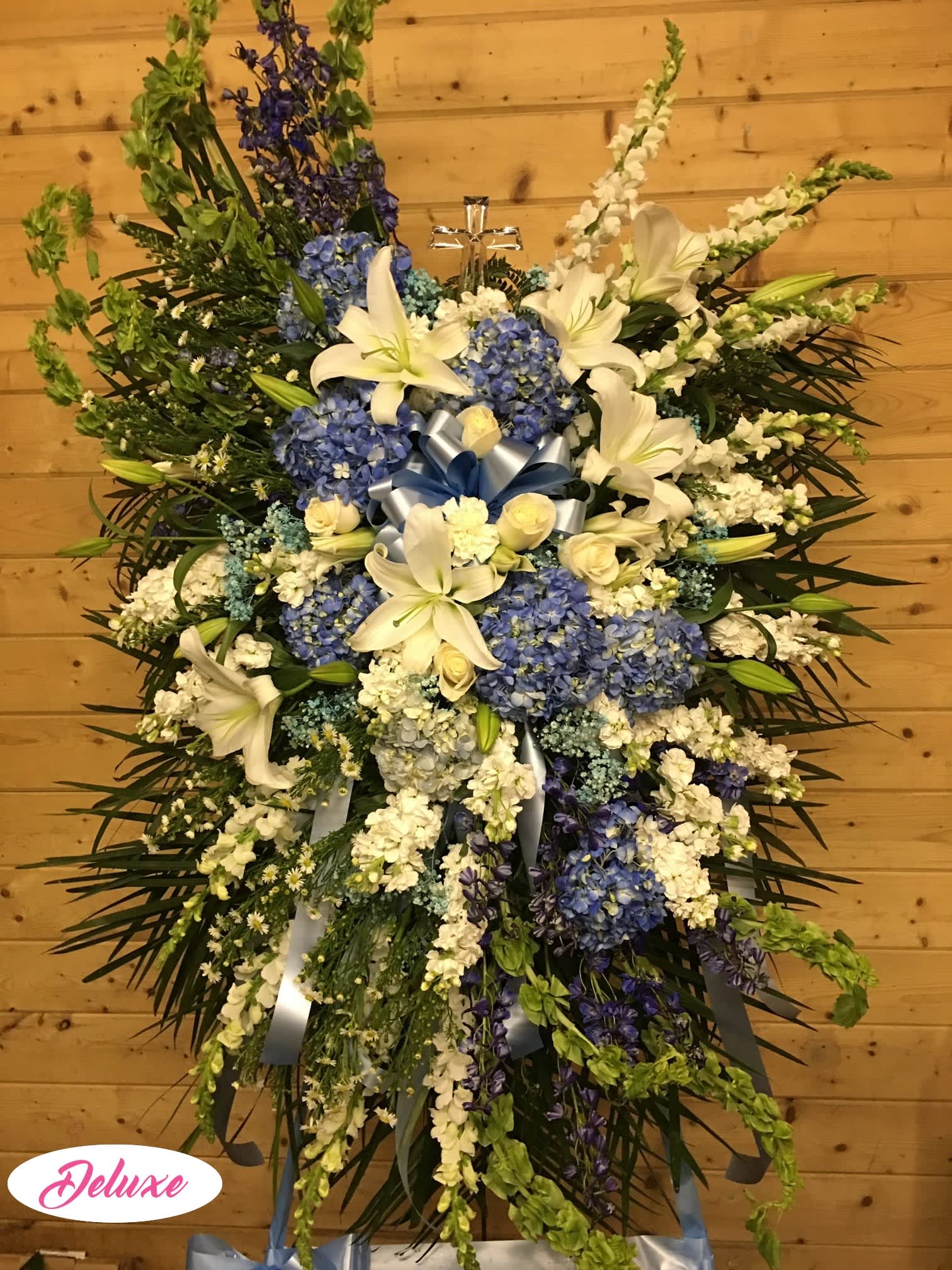 Large standing spray of white lilies and blue hydrangeas with ribbon accents