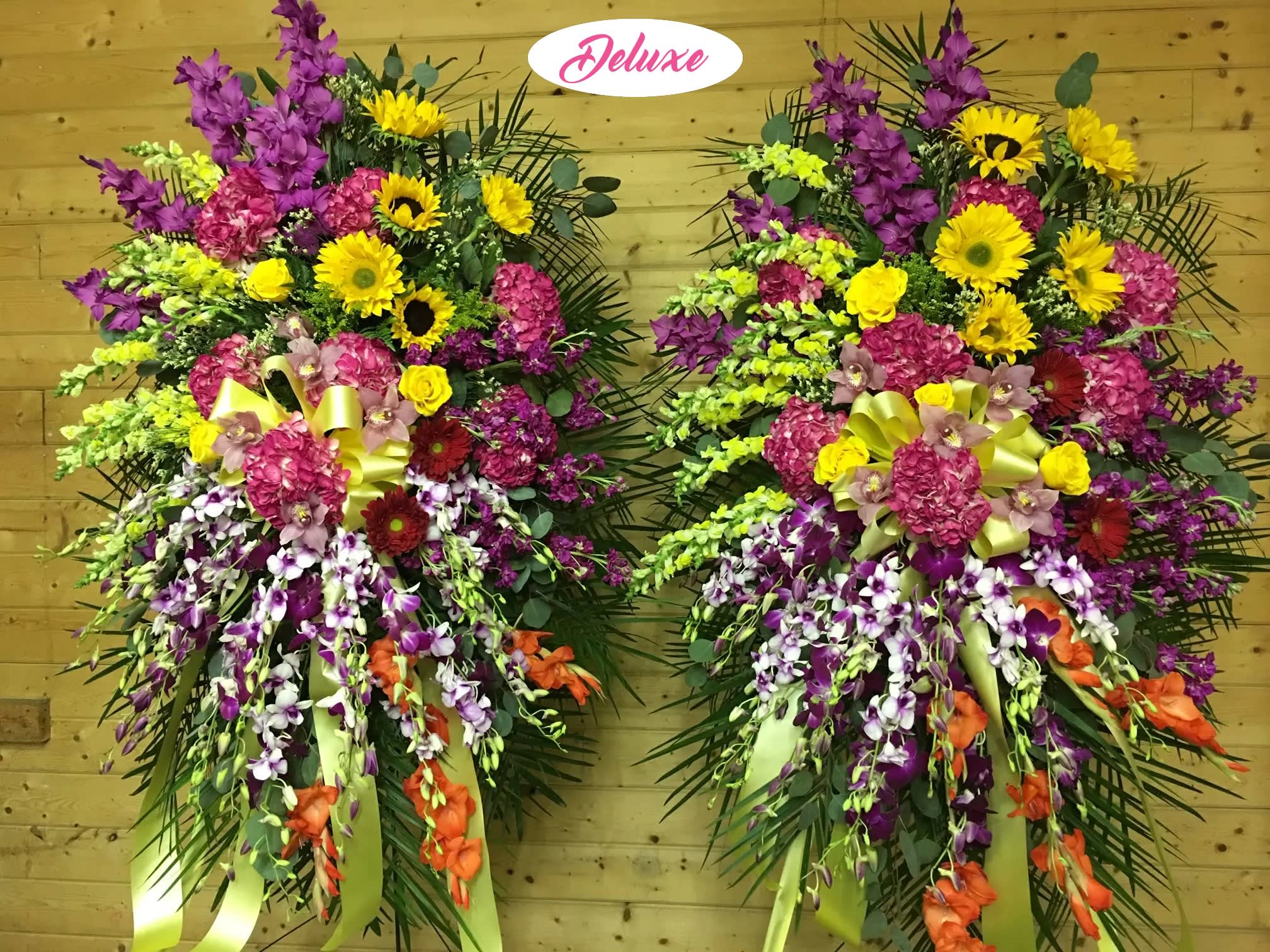 Two large standing floral sprays with yellow, pink, purple, and orange flowers